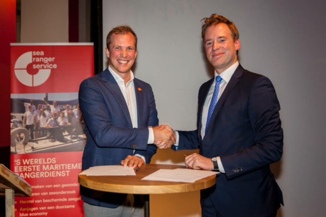 Wietse van der Werf, founder and CEO of Sea Ranger Service, shakes hands with Koen van Swam, general manager of the North Sea Farm Foundation, over a signed contract.
