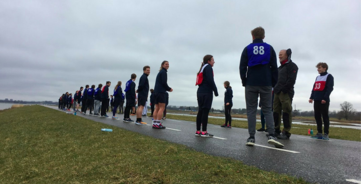 A large number of bootcamp participants in exercise clothing getting ready for a run on a gray, overcast day.