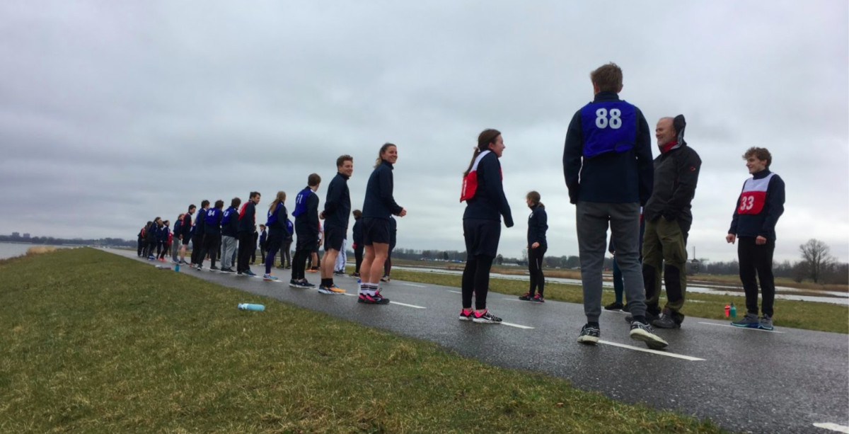 A large number of bootcamp participants in exercise clothing getting ready for a run on a gray, overcast day.