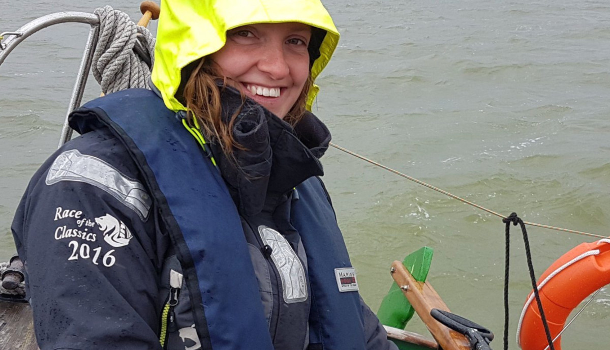A close up of Sea Ranger Vera, on board a Sea Ranger vessel out at sea. Vera has a florescent yellow hood up and is smiling at the camera.