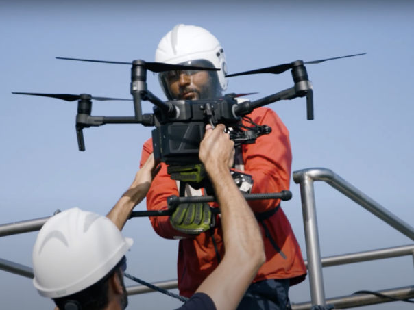 Two Sea Rangers on a boat, out at sea, setting up a drone to carry out ocean conservation work.