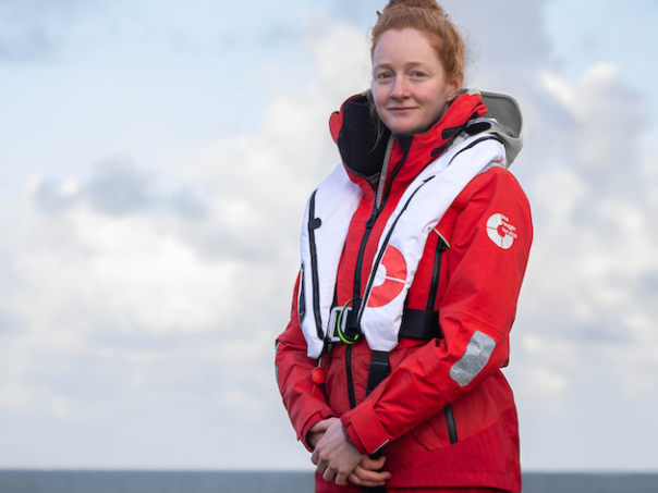 A female Sea Ranger in uniform posing in front of a sea scape.
